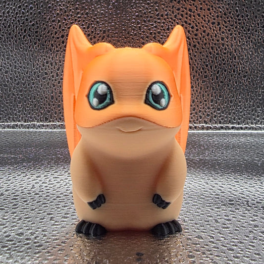 Small figurine of a cat with large eyes on a textured surface