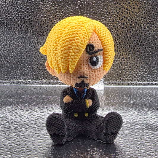 Small crocheted figure with blonde hair and black clothing on a textured gray background