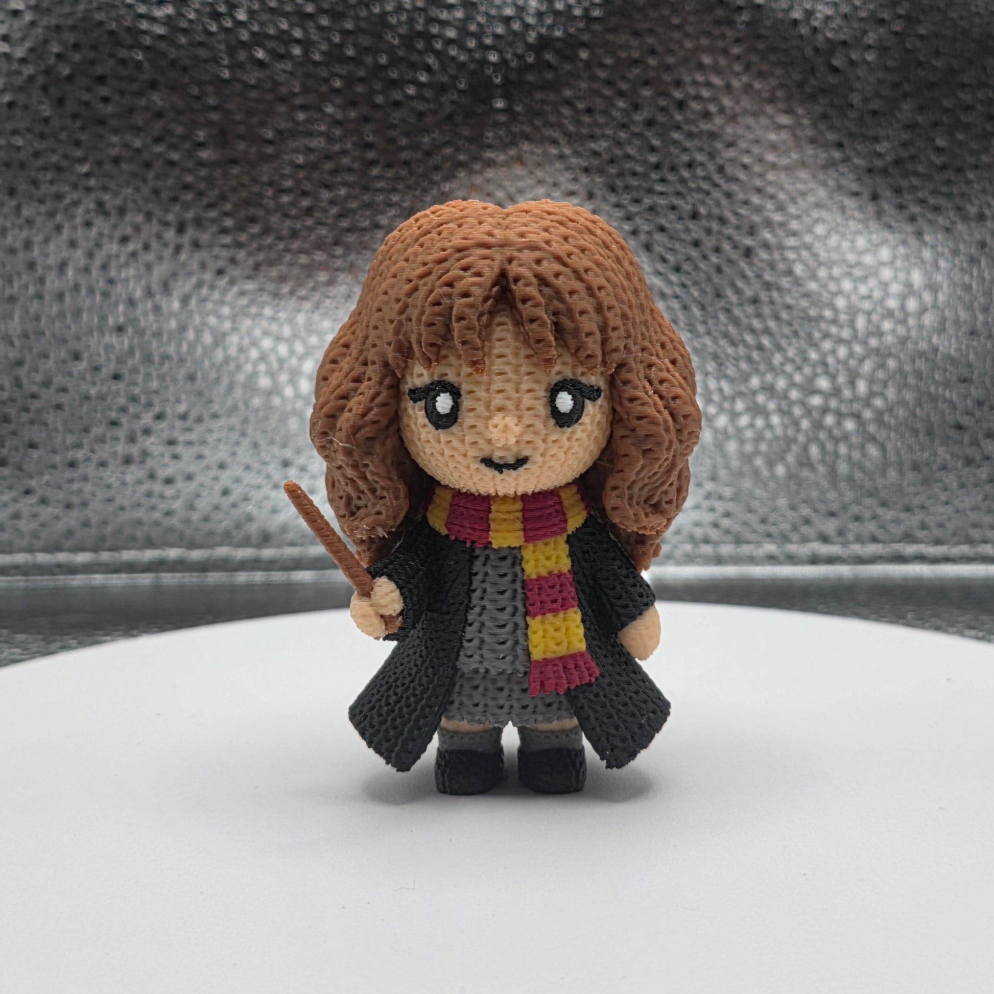Small plush toy of a character with a scarf on a textured surface
