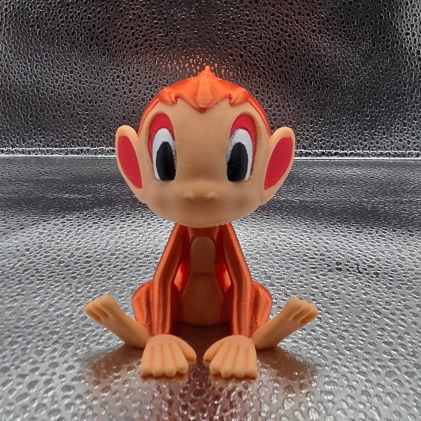 Small orange and beige figurine on a textured metallic surface