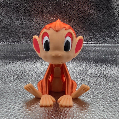 Small orange and beige figurine on a textured metallic surface