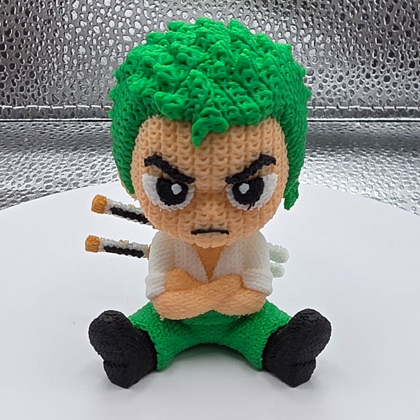 Crocheted character with green hair and black shoes on a metallic surface