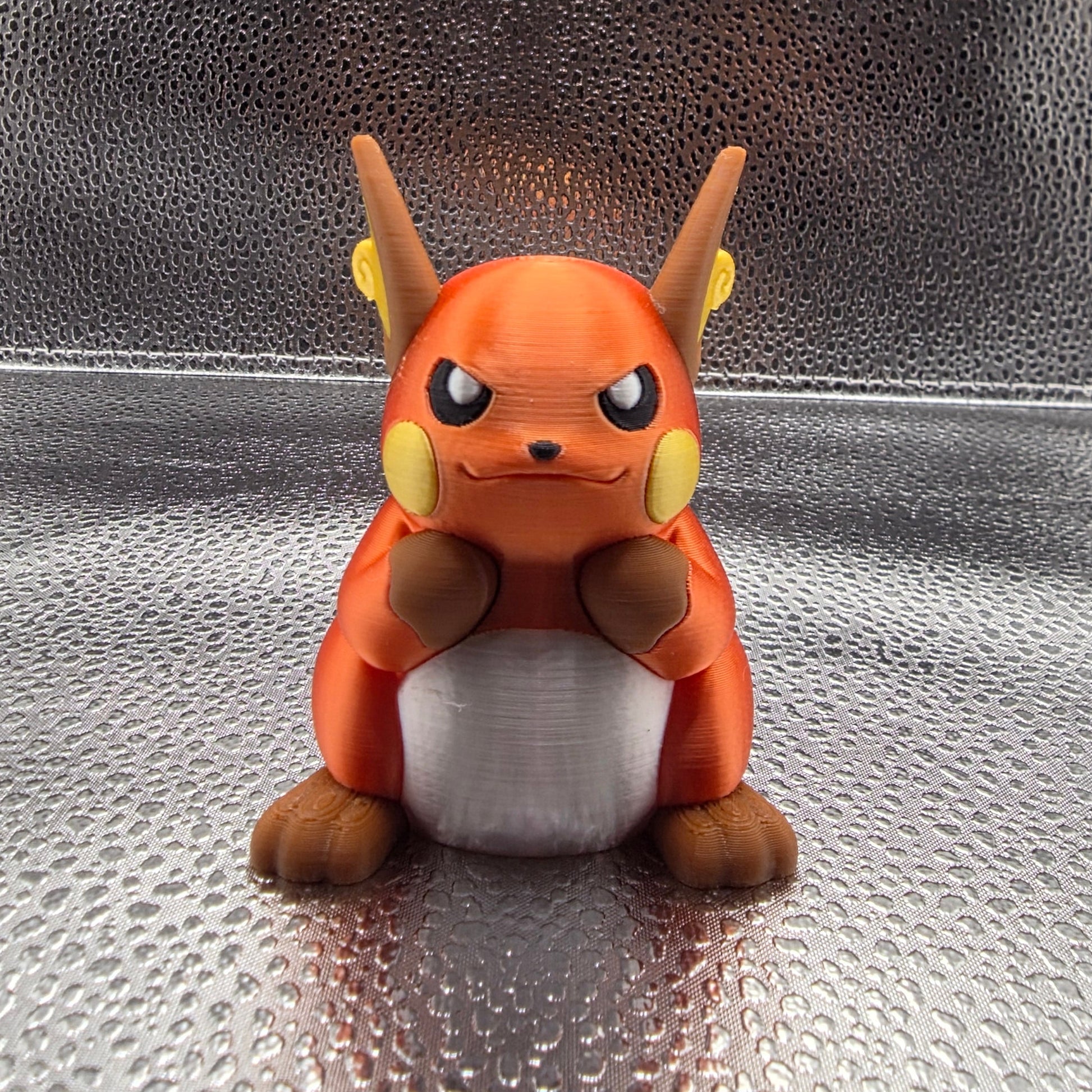 Small figurine of a stylized animal character on a textured metallic surface