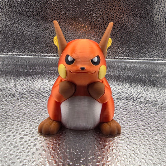 Small figurine of a stylized animal character on a textured metallic surface